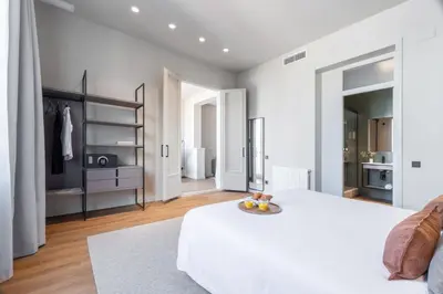 a white bedroom with a bed and a tv at Aspasios Rambla Catalunya Apartments in Barcelona