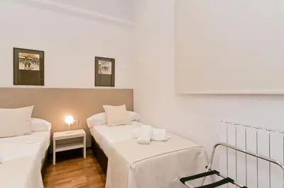a room with two beds and a table with a lamp at Aspasios Rambla Catalunya Apartments in Barcelona