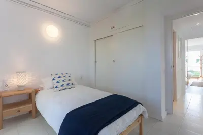 a white bedroom with a bed and a table at Relaxing Seafront Apartment Gavà 20 Min from BCN in Gavà
