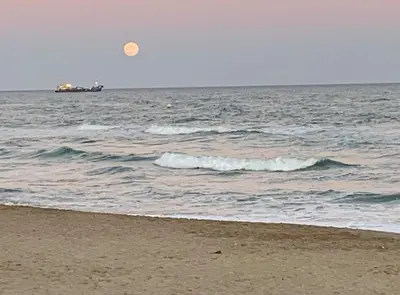 a boat in the ocean with a beach with waves at Siroco by Seaside Homes in Castelldefels