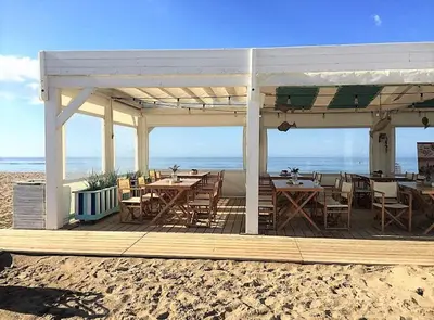 a restaurant on the beach with tables and chairs at Siroco by Seaside Homes in Castelldefels
