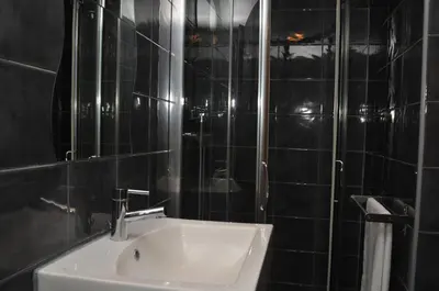 a black tiled bathroom with a sink and a shower at Hotel Ibiza in Sitges