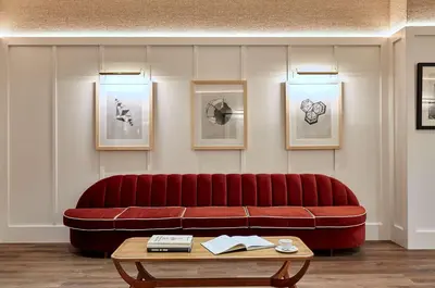 a red couch in a room with a table at Radisson Blu 1882 Hotel, Barcelona Sagrada Familia in Barcelona