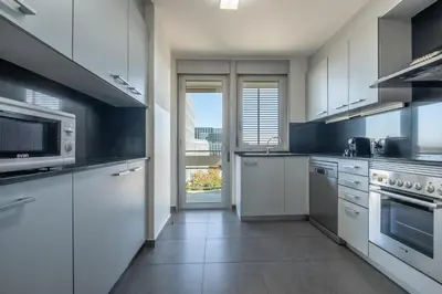 a kitchen with white cabinets and a large window at Rent Top Apartments Forum in Sant Adria de Besos