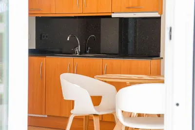 a kitchen with white chairs and a table at MAREA Hotel in Vilanova i la Geltrú