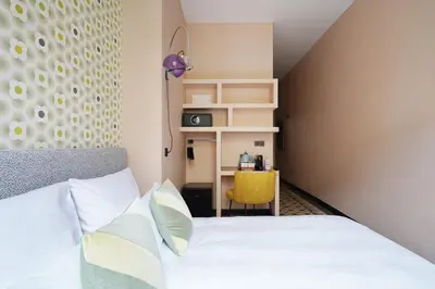 a bedroom with a bed and a yellow chair at Numa Barcelona Roca in Barcelona