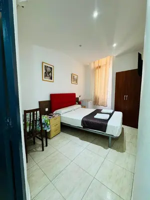 a bedroom with two beds and a red couch at Hostal Mont Thabor in Barcelona