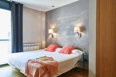 a bedroom with a bed with white sheets and orange pillows at AinB Sagrada Familia Apartments in Barcelona