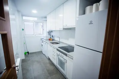 a white kitchen with a sink and a refrigerator at Manresa Apartamentos Turísticos in Manresa