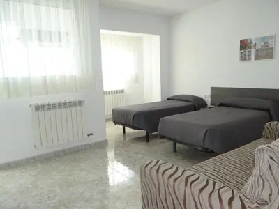 a bedroom with three beds and a window at Manresa Apartamentos Turísticos in Manresa