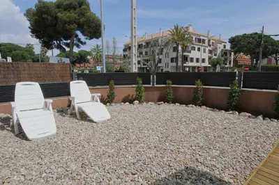a group of white chairs sitting on a gravel patio at Beach House Castelldefels in Castelldefels