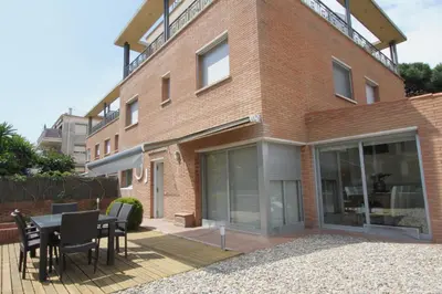 a building with a patio with a table and chairs at Beach House Castelldefels in Castelldefels
