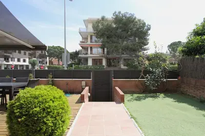 a small backyard with a fence and a table and a lawn at Beach House Castelldefels in Castelldefels