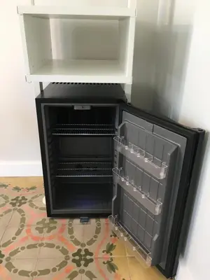 a black refrigerator with its door open on a floor at Habitació amb encant in Sitges