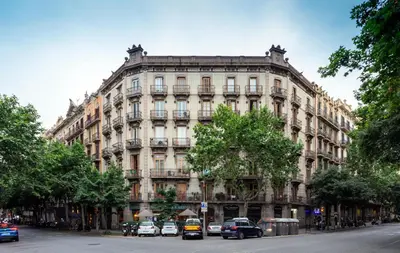 a large building with cars parked in front of it at Primavera Hostel in Barcelona