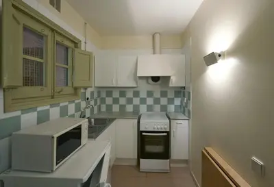a small kitchen with white cabinets and a microwave at Apartamentos Montserrat Abat Marcet in Montserrat