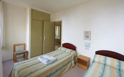a bedroom with two beds and a chair in it at Apartamentos Montserrat Abat Marcet in Montserrat