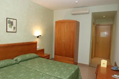 a bedroom with a green bed and a wooden cabinet at Hotel Fonda Neus in Sant Sadurní dʼAnoia