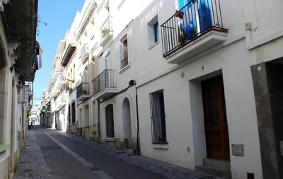 an empty alley with white buildings with balconies at Sitges Ático 2 min a Playa San Sebastían in Sitges