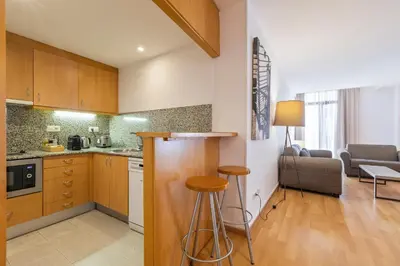 a kitchen with wooden cabinets and a living room at Aspasios Plaza Real Apartments in Barcelona