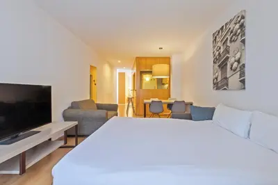 a hotel room with a bed and a living room at Aspasios Plaza Real Apartments in Barcelona