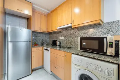 a kitchen with a refrigerator and a washer and dryer at Aspasios Plaza Real Apartments in Barcelona