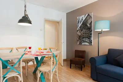 a living room with a dining room table and a blue couch at MH Apartments Ramblas in Barcelona