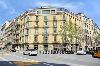 a large yellow building on a city street with cars at Hotel Vasanta in Barcelona