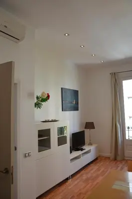 a white living room with a television and a desk at Claris Apartments in Barcelona