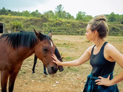 a young woman is petting a brown horse at El Molí Blanc in Lavid
