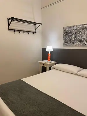 a bedroom with a bed and a table with a lamp at Hostal El Ninot in Barcelona