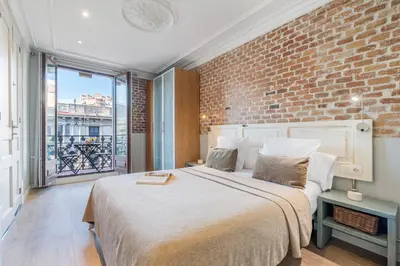 a bedroom with a large bed and a brick wall at Fuster Apartments by Aspasios in Barcelona