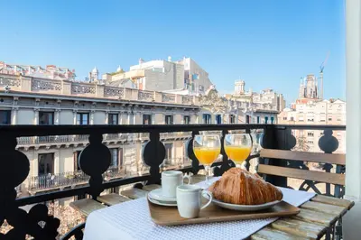 a table with two glasses of orange juice and croissants on a balcony at Fuster Apartments by Aspasios in Barcelona