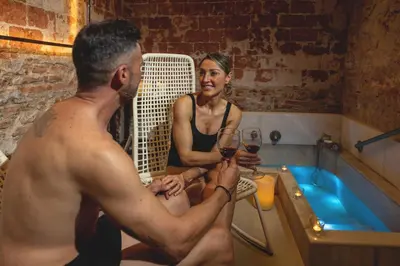 a man and a woman sitting in a tub with wine at RVHotels Broquetas Spa Termal in Caldes de Montbui