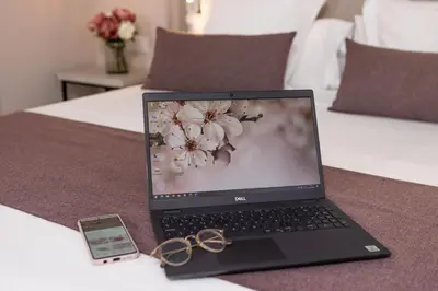 a laptop computer on a bed with a cell phone and scissors at RVHotels Broquetas Spa Termal in Caldes de Montbui