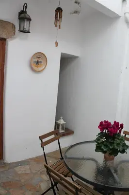 a glass table with a vase of flowers and two chairs at Old Navy House in Badalona