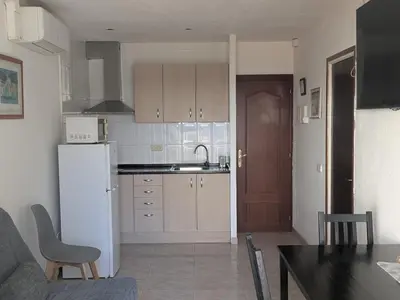a kitchen with a white refrigerator and a table at Apartamentos Mitus in Canet de Mar