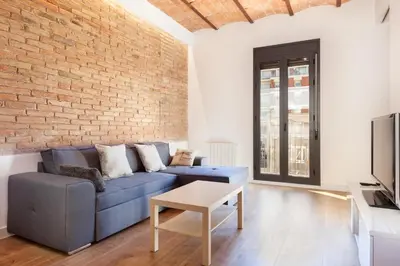 a living room with a blue couch and a brick wall at Akira Flats Urgell apartment in Barcelona