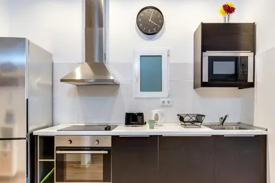 a kitchen with a sink and a clock on the wall at Charming & Convenient Apartment Near Plaza Espanya in Barcelona