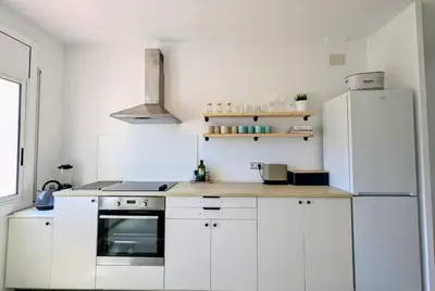 a kitchen with white cabinets and a white refrigerator at Charming Attic with Pool and Seaviews in Arenys de Mar
