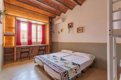 a bedroom with a bed and a desk and a window at Bird House in Barcelona