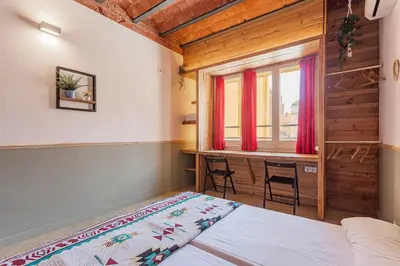 a bedroom with a bed and a desk and a window at Bird House in Barcelona