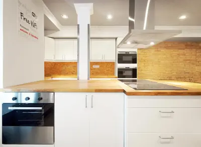 a kitchen with white cabinets and a brick wall at Black Swan Hostel Barcelona in Barcelona