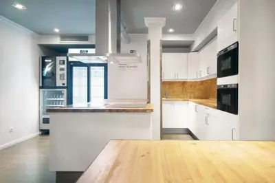 a kitchen with white cabinets and a wooden counter top at Black Swan Hostel Barcelona in Barcelona
