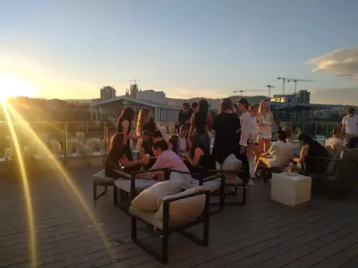 a group of people sitting on a deck at sunset at Twentytu Hostel Barcelona in Barcelona