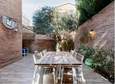 a wooden table and chairs in a courtyard at Bonito duplex con piscina en Barcelona&playa in Tiana