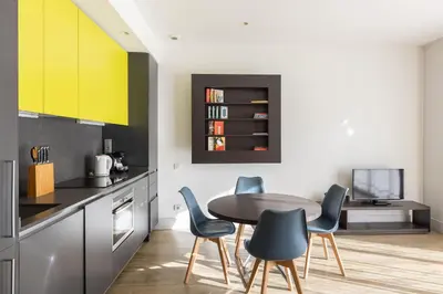 a kitchen with yellow cabinets and a table and chairs at Cosmo Apartments Passeig de Gràcia in Barcelona