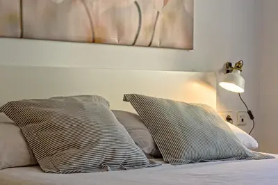 a bed with two pillows and a lamp on it at Apartamento&piscina cerca de Barcelona in Ripollet