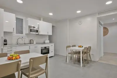 a kitchen with white cabinets and a table and chairs at Stay Together Barcelona Apartments in Barcelona