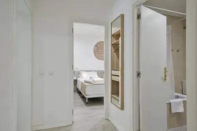 a white bathroom with a mirror and a bed at Stay Together Barcelona Apartments in Barcelona